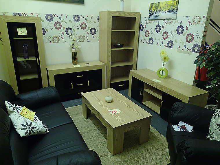 Furniture on display including a leather black sofa and tv stand.